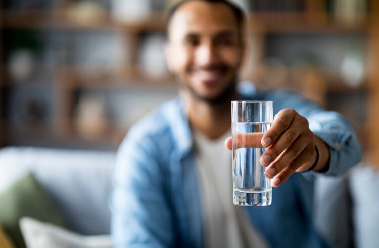 man holds drinking water in arm outstreched man holds drinking water in outstretched arm